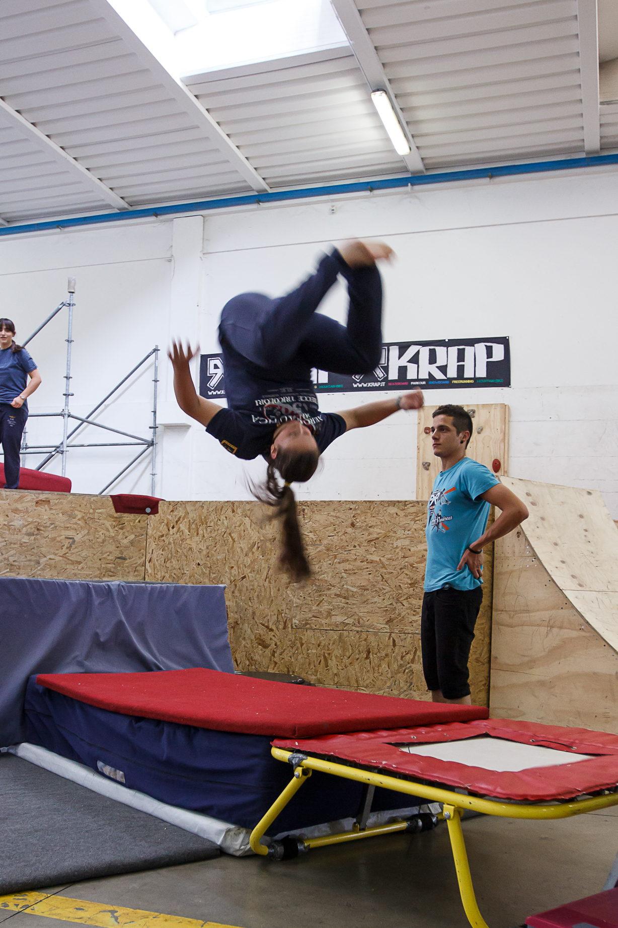 Una ragazza esegue un salto acrobatico all'indietro mentre l'istruttore la segue da terra